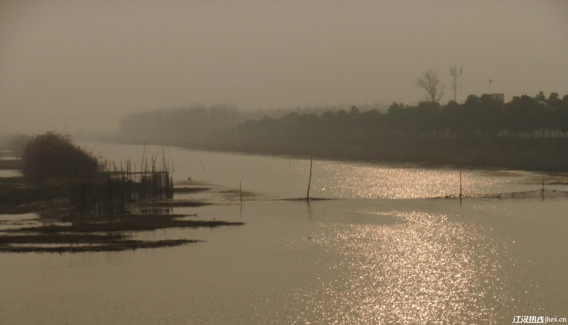 平静的河面波光粼粼,近处一只橙色的海绵宝宝风筝和远处一只鹰形风筝的线缠在了一起